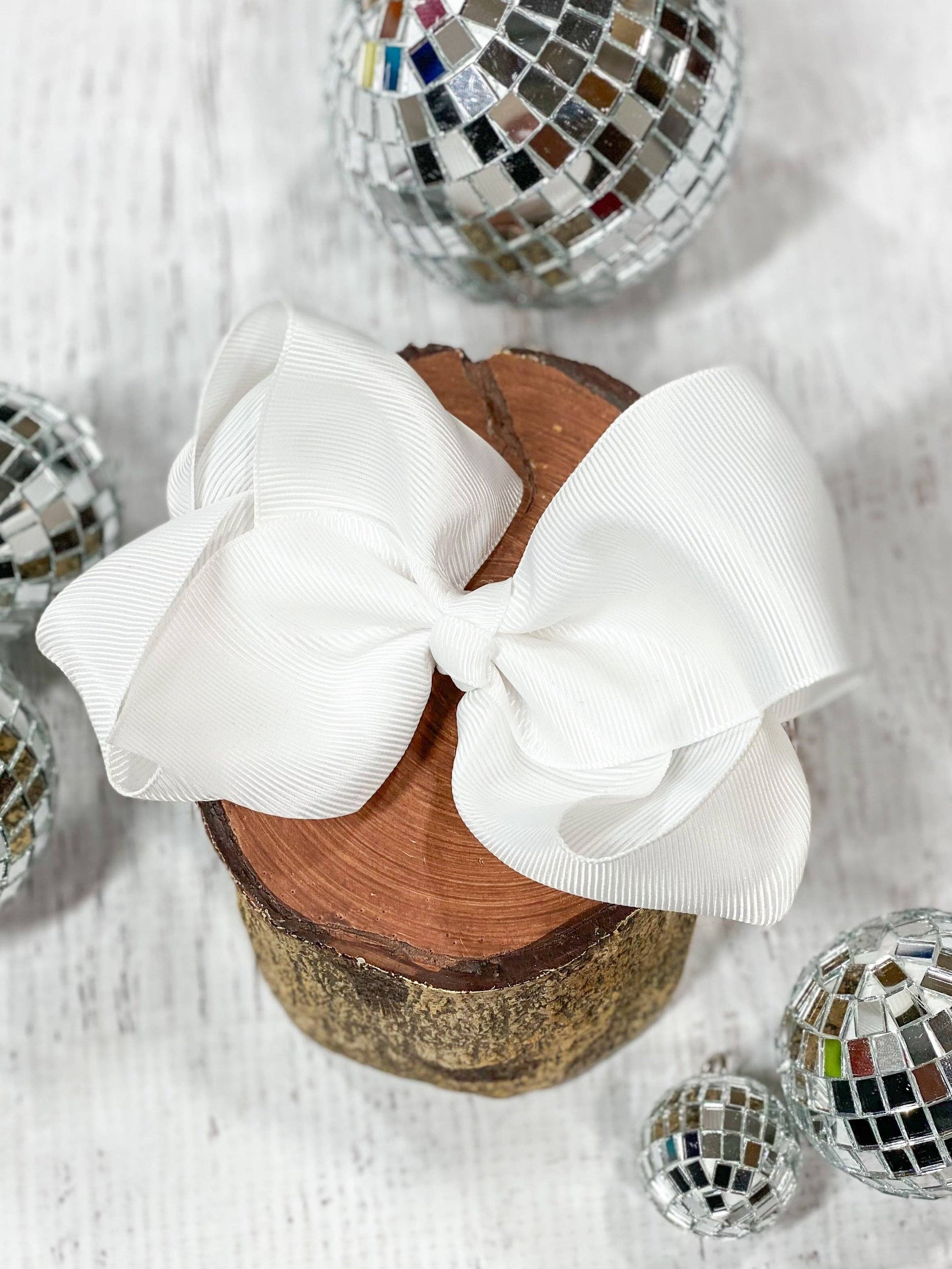White bow on a wooden block with disco balls around