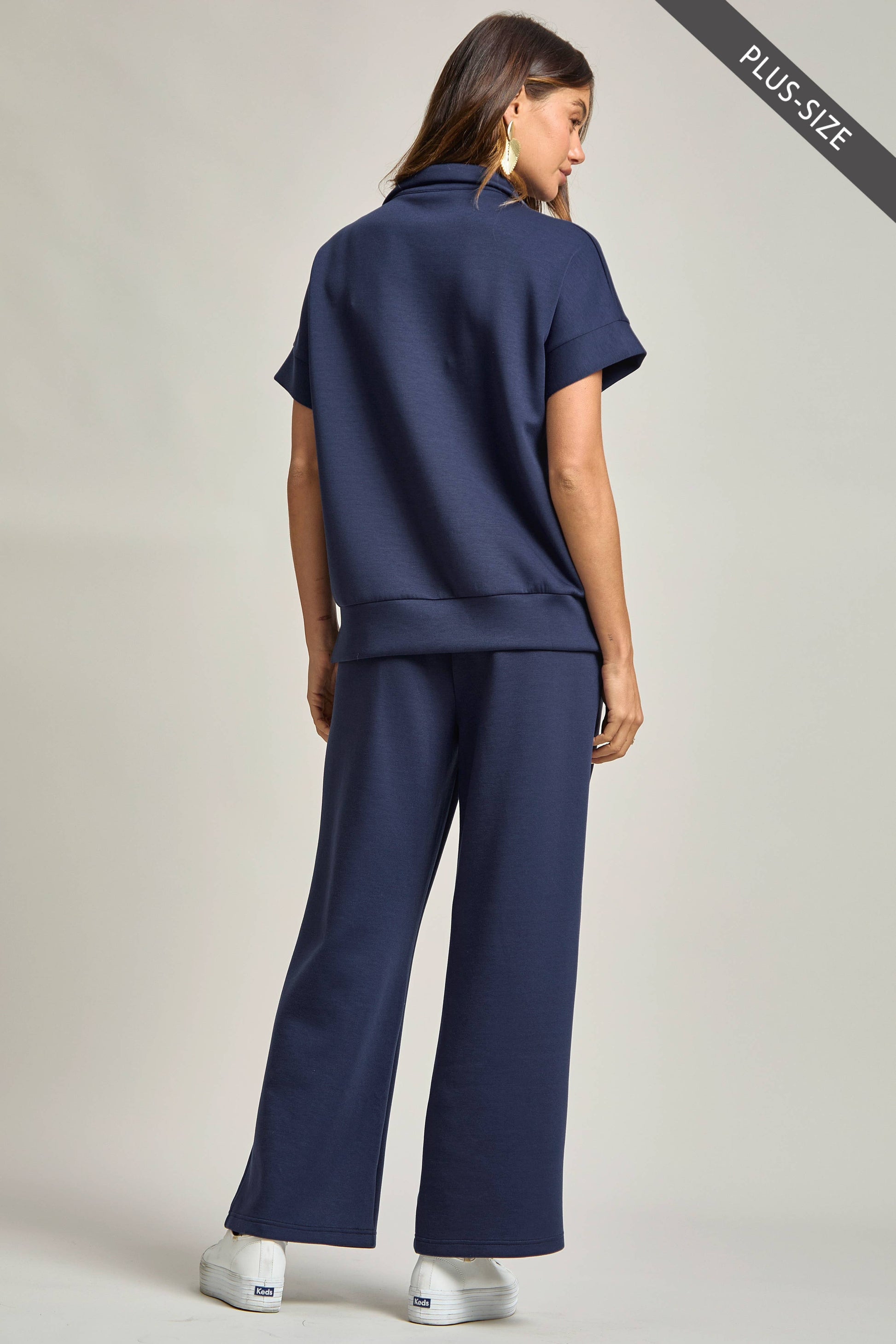 Woman wearing a navy blue outfit on a plain background