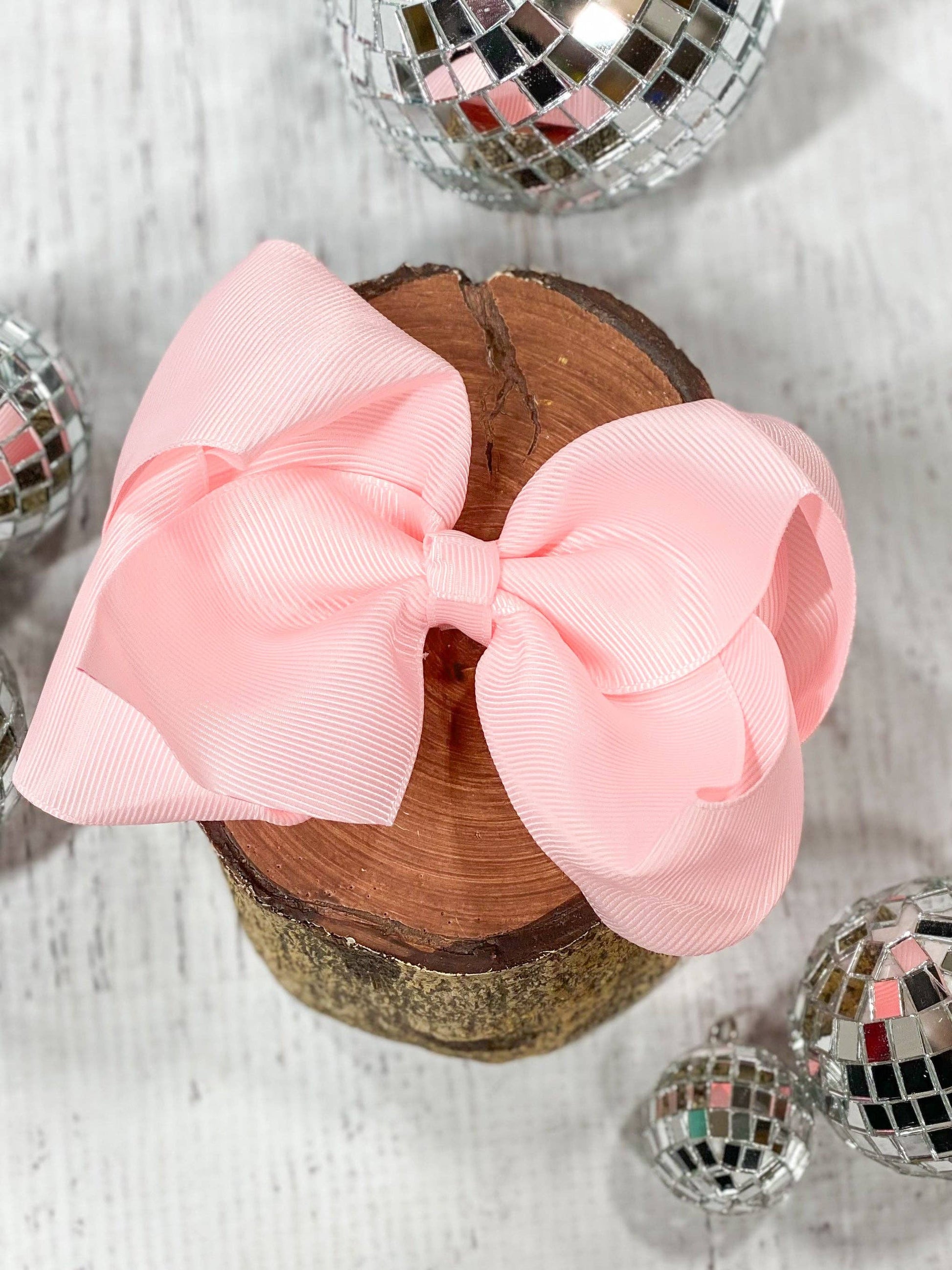 Pink bow on a wooden block with disco balls around