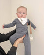 Baby holding pacifier with linen clip attached to outfit