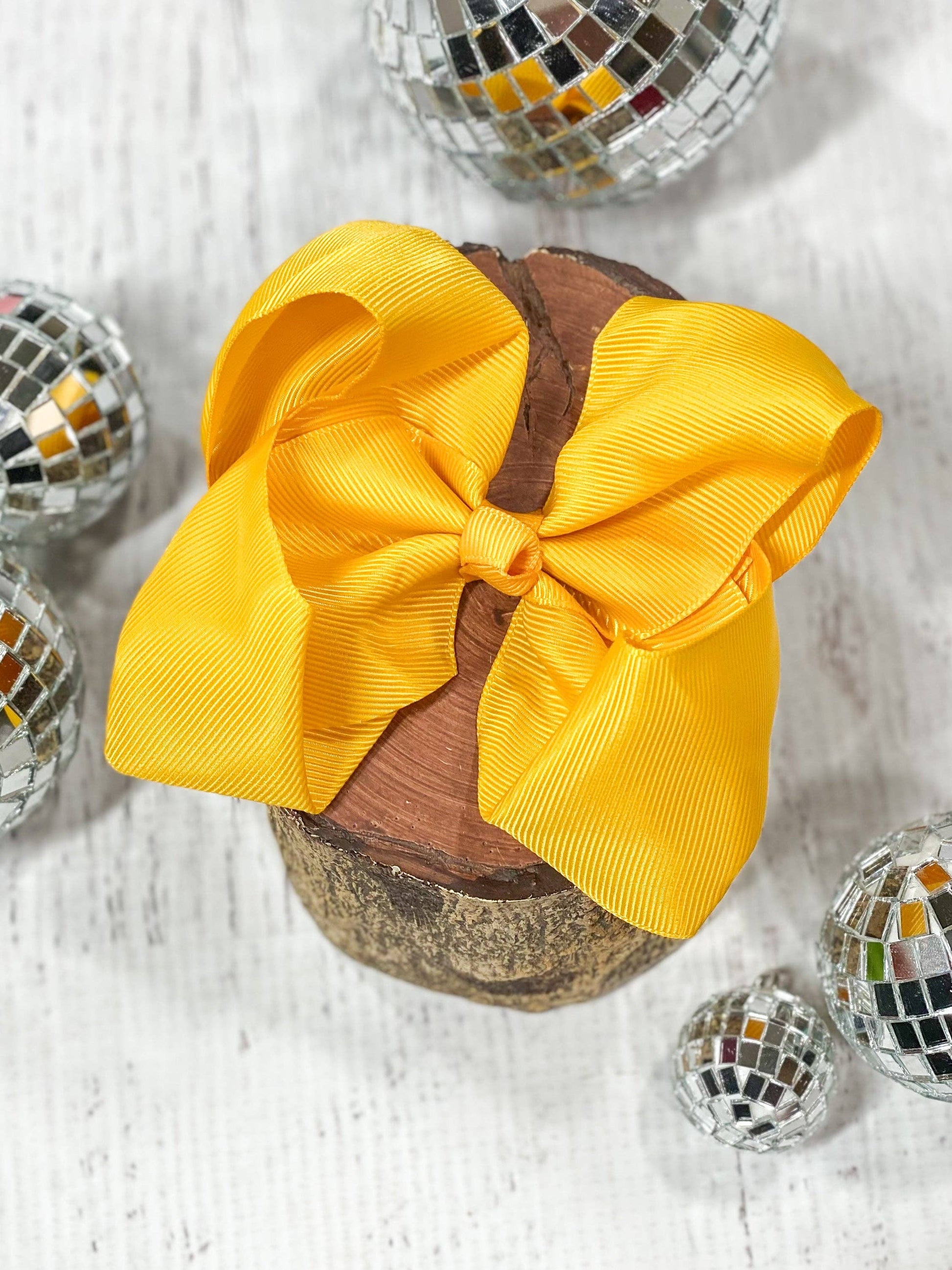 Yellow hair bow on a wooden block with disco balls around