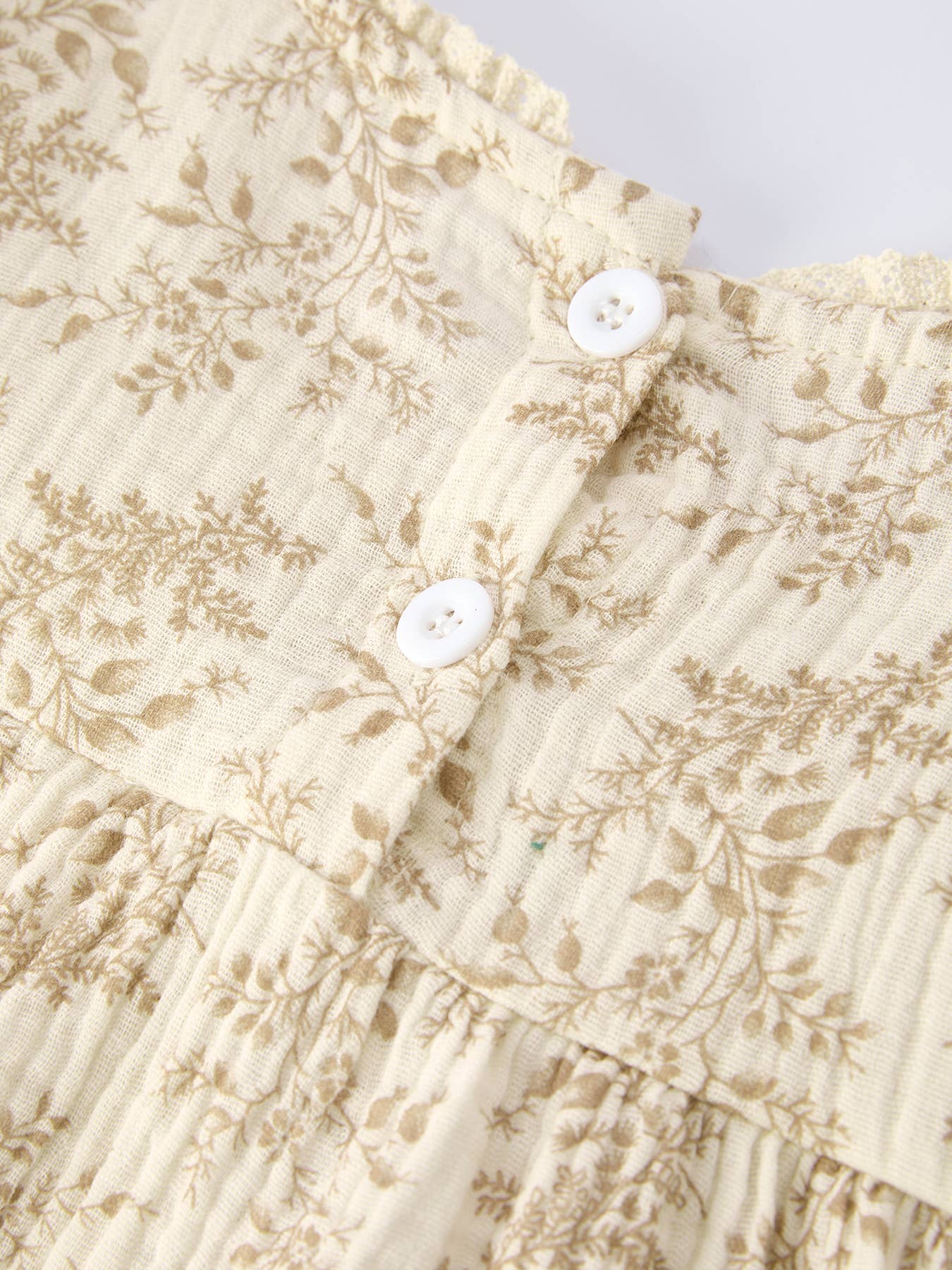 Close-up of a floral-patterned fabric with white buttons on a light background