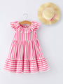 Pink and white striped dress on a hanger with a straw hat on a light gray background