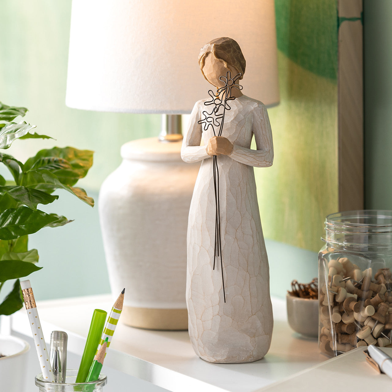 Decorative figurine on a desk with a lamp and stationery items