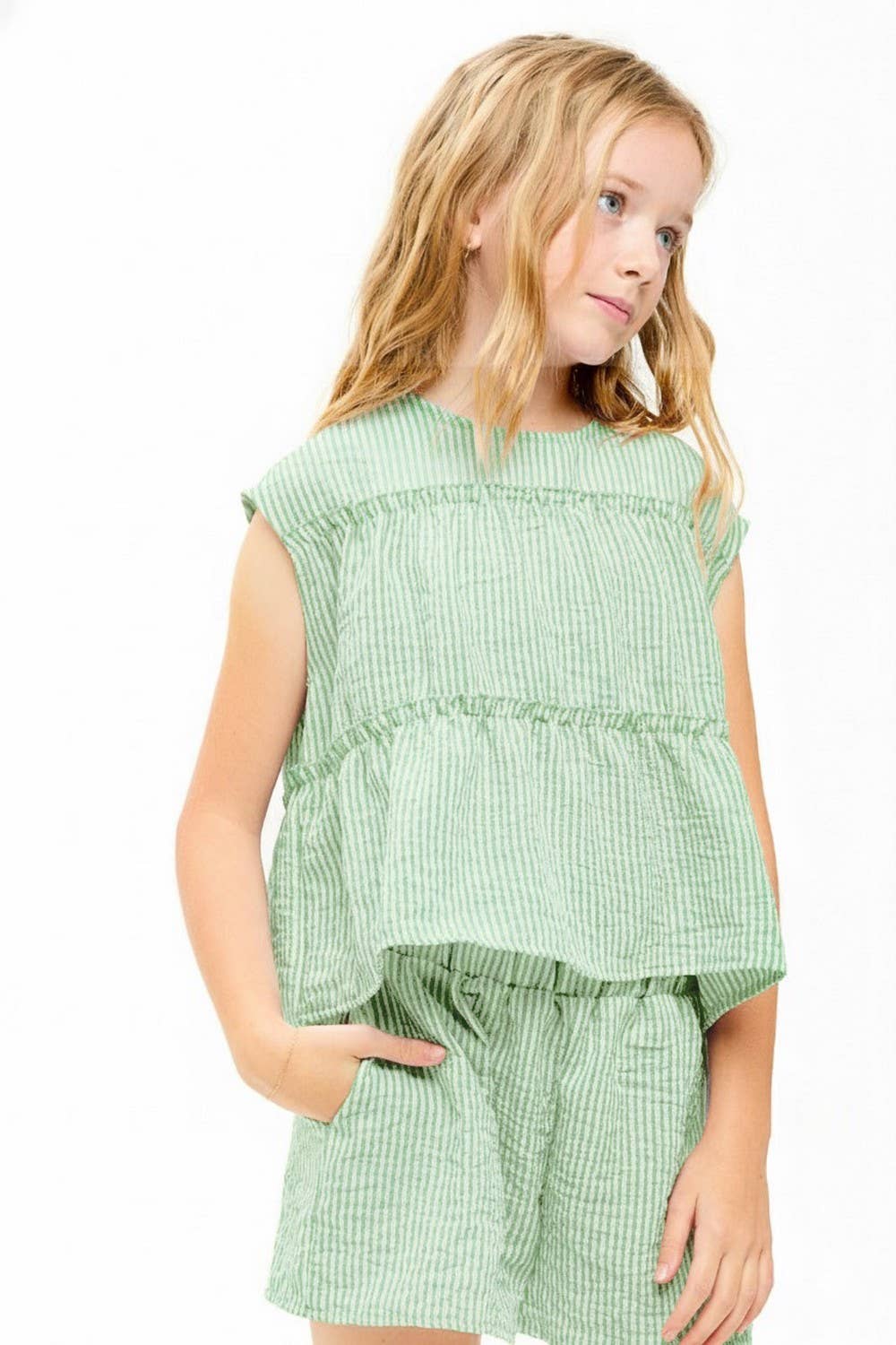 Young girl wearing a green checkered outfit on a white background