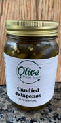 Jar of candied jalapenos with a gold lid on a wooden surface