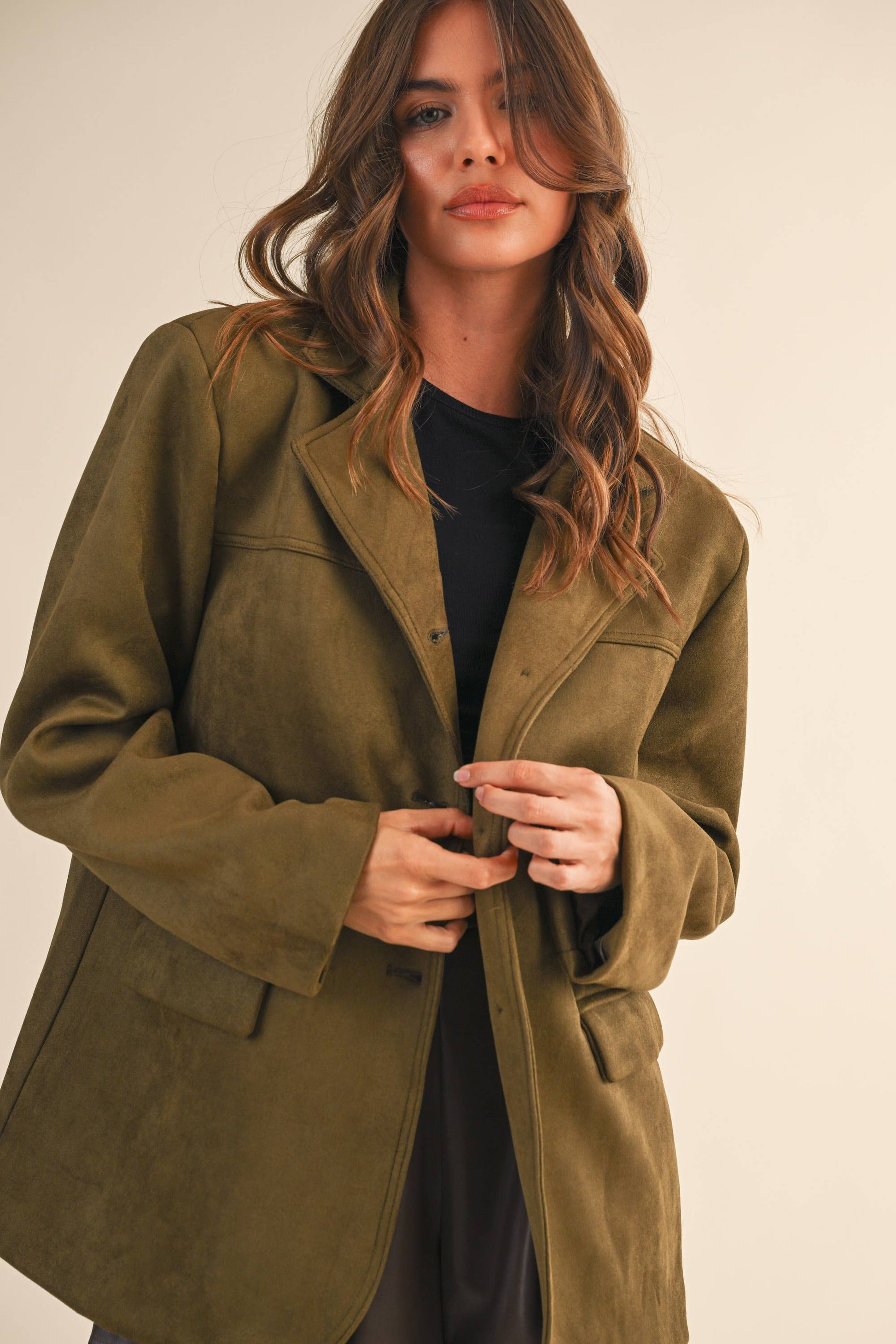 Woman wearing a green coat against a plain background