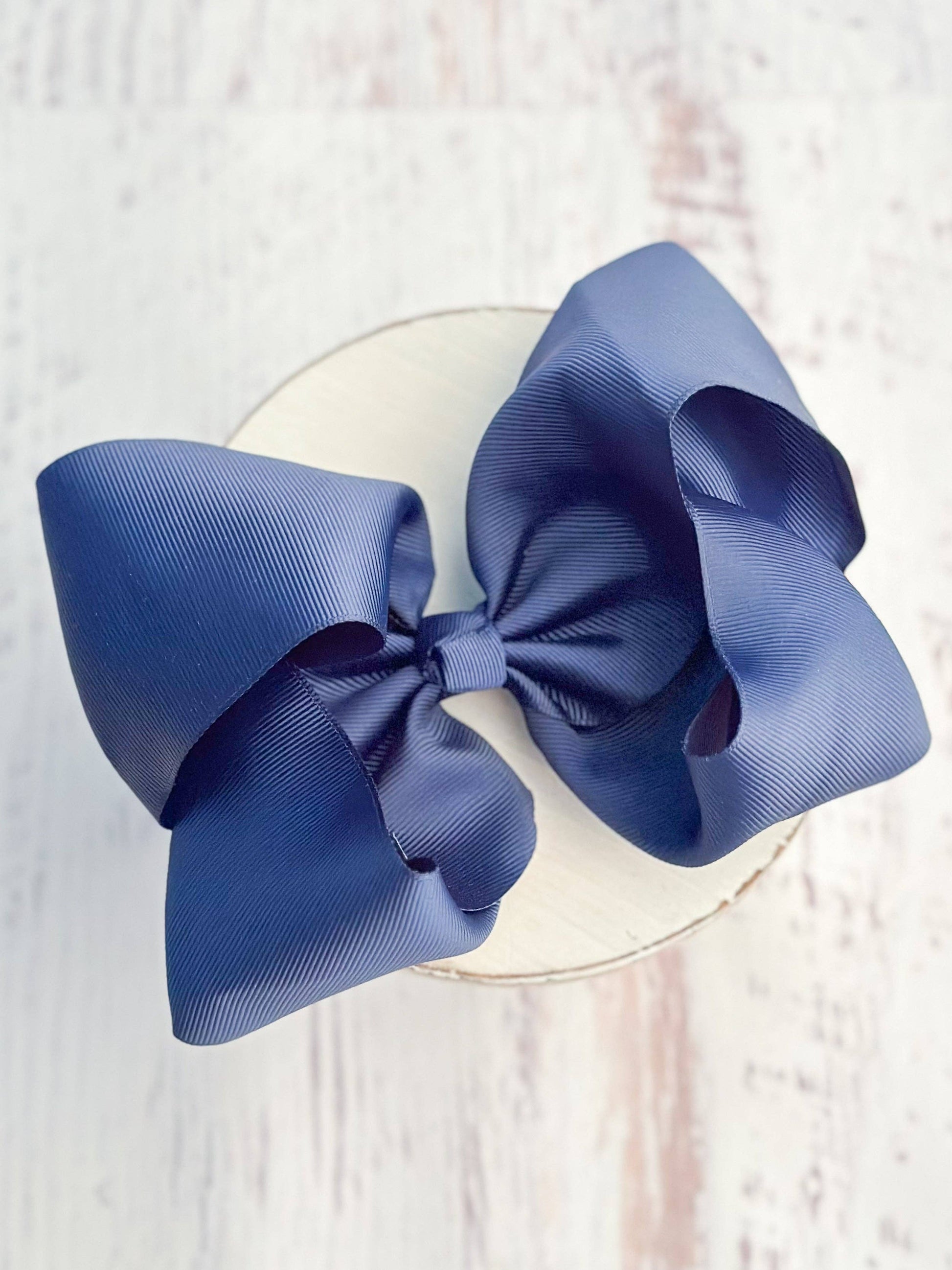 Large blue bow on a clear stand against a light wooden background