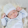 Newborn baby wrapped in a light blue blanket and wearing a matching hat, lying on a soft surface.