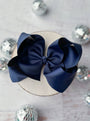 Navy blue hair bow on a white surface with decorative silver balls.