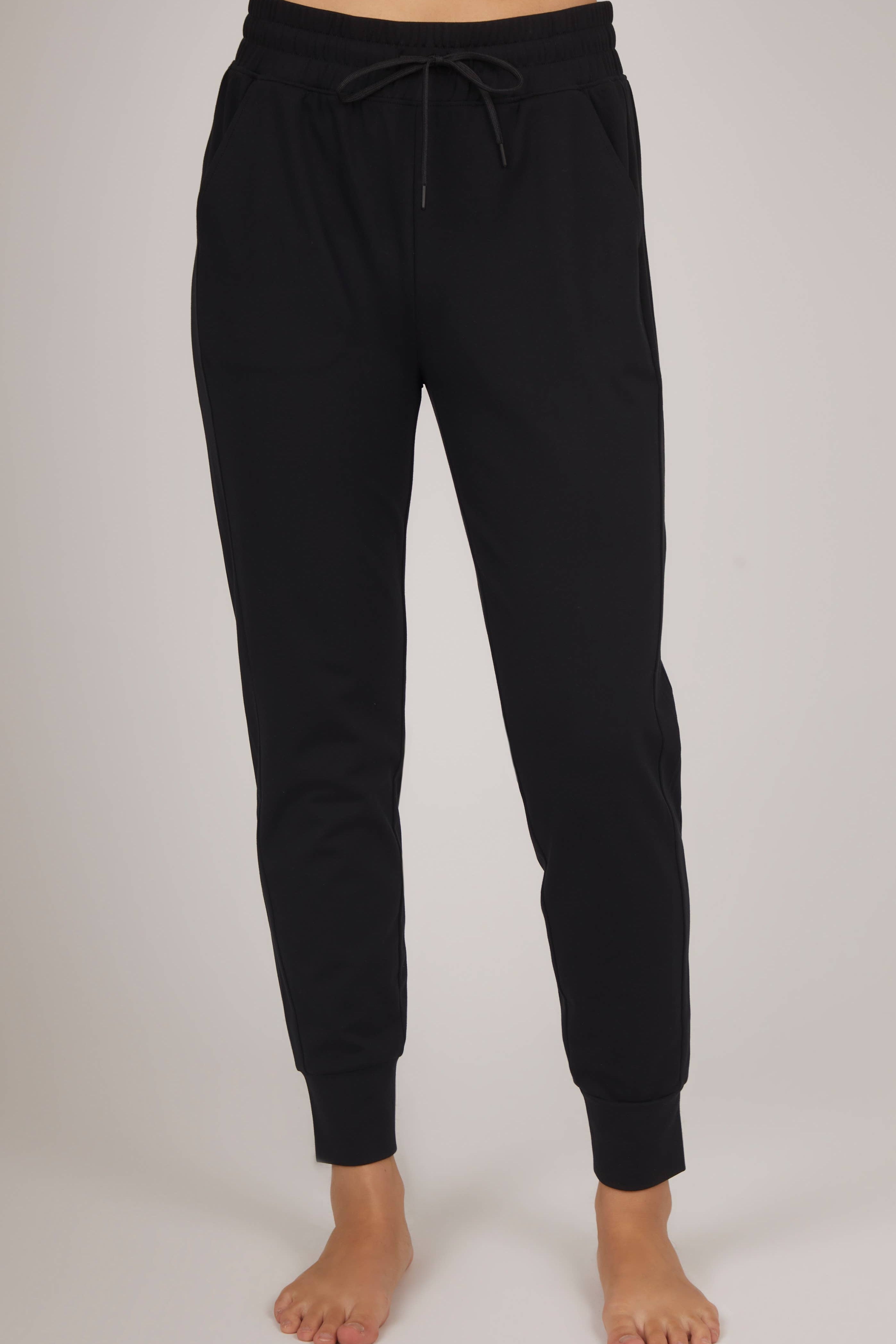 Black jogger pants worn by a person on a plain background