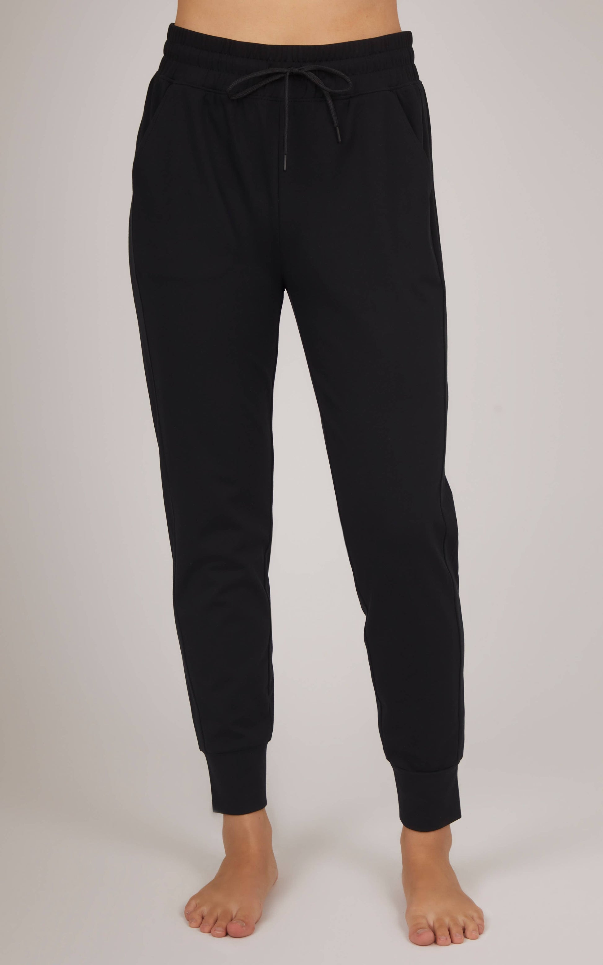 Black jogger pants worn by a person on a plain background