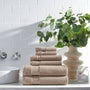 Stack of beige towels on a bathroom counter with a plant and decorative items.