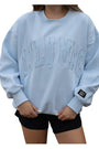 Light blue sweatshirt with 'LULU MEG' text worn by a person on a white background
