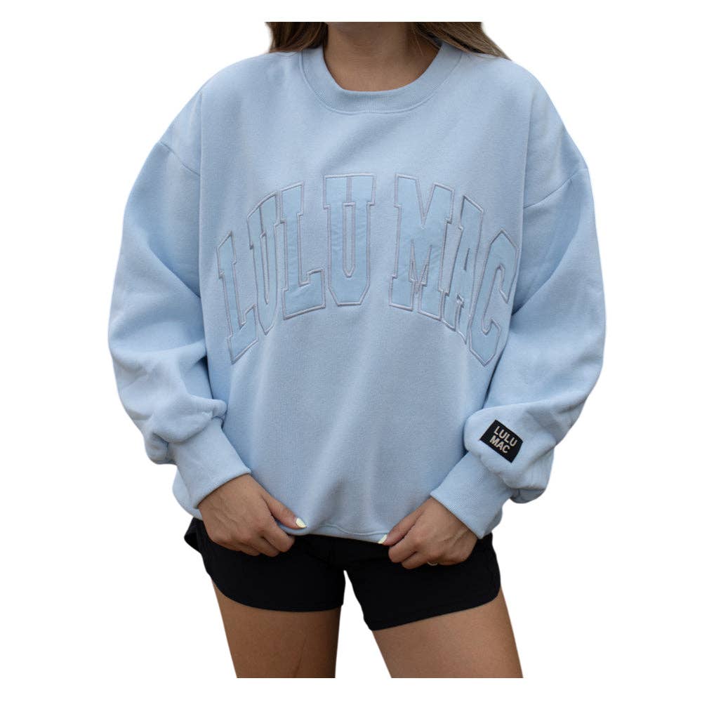Light blue sweatshirt with 'LULU MEG' text worn by a person on a white background