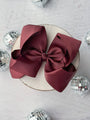 Large burgundy bow on a white cake with disco balls in the background