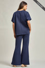 Woman wearing a navy blue outfit with wide-leg pants on a plain background