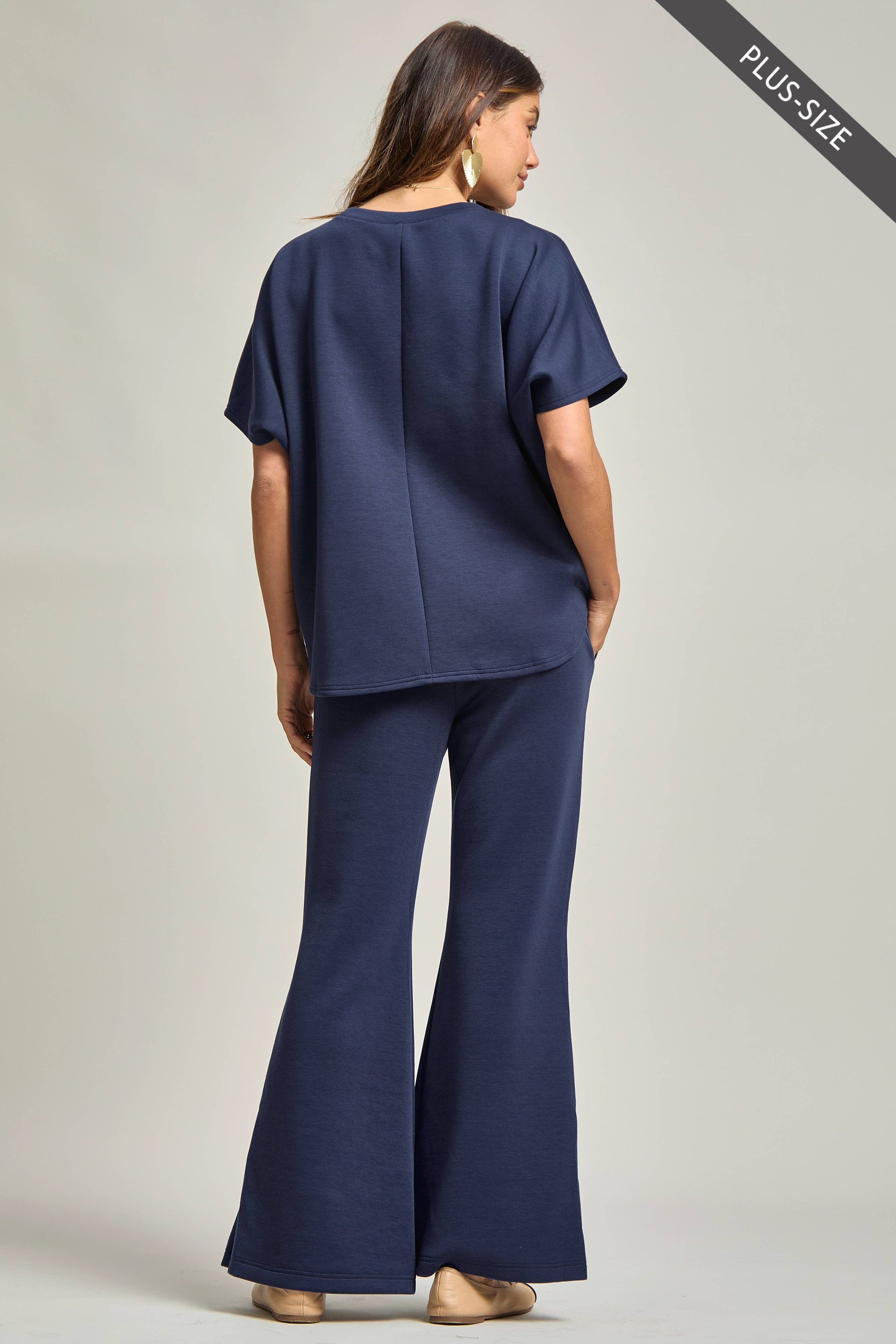 Woman wearing a navy blue outfit with wide-leg pants on a plain background