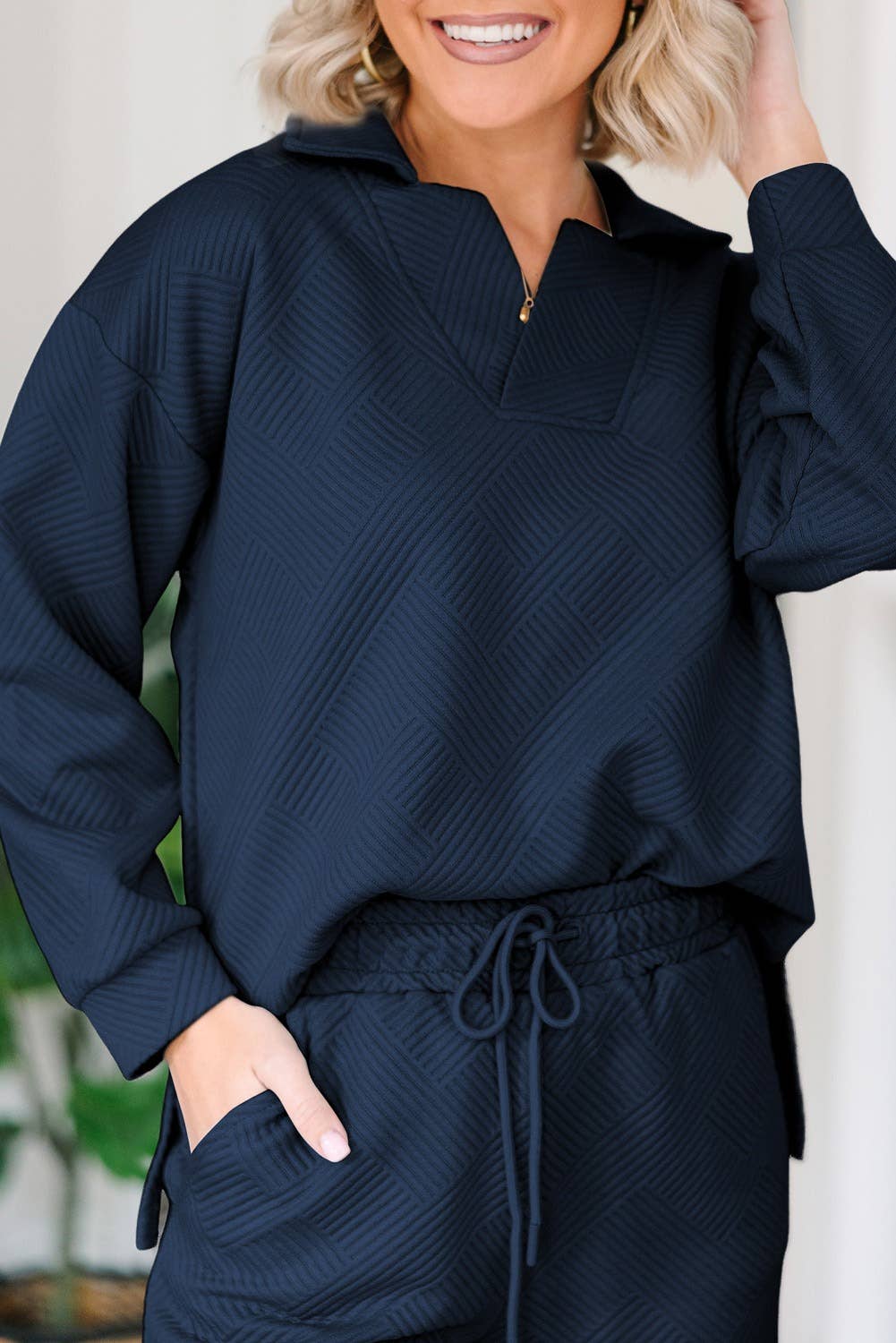 Person wearing a navy blue textured outfit with a blurred background
