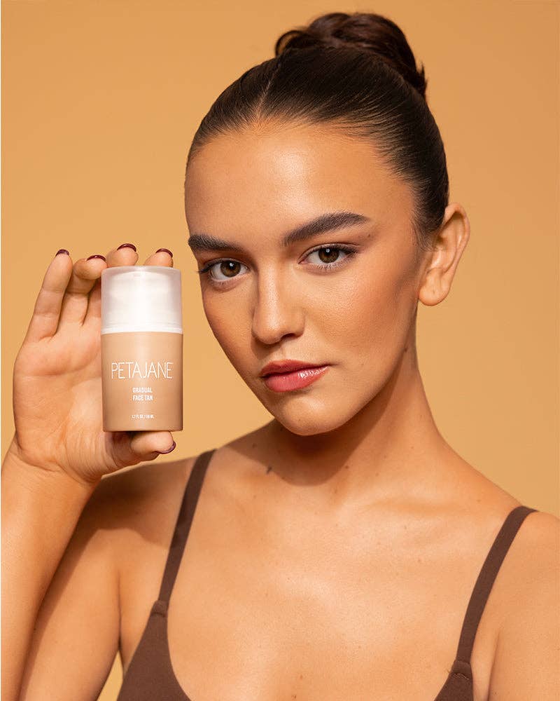 Woman holding a skincare product against a beige background