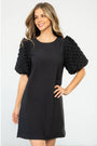 Woman wearing a black dress with textured sleeves on a white background