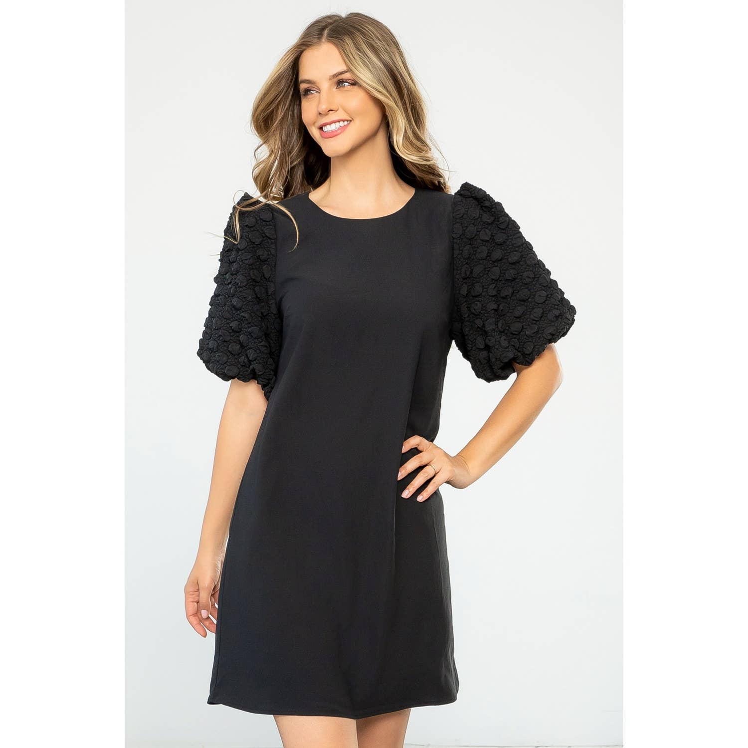 Woman wearing a black dress with textured sleeves on a white background