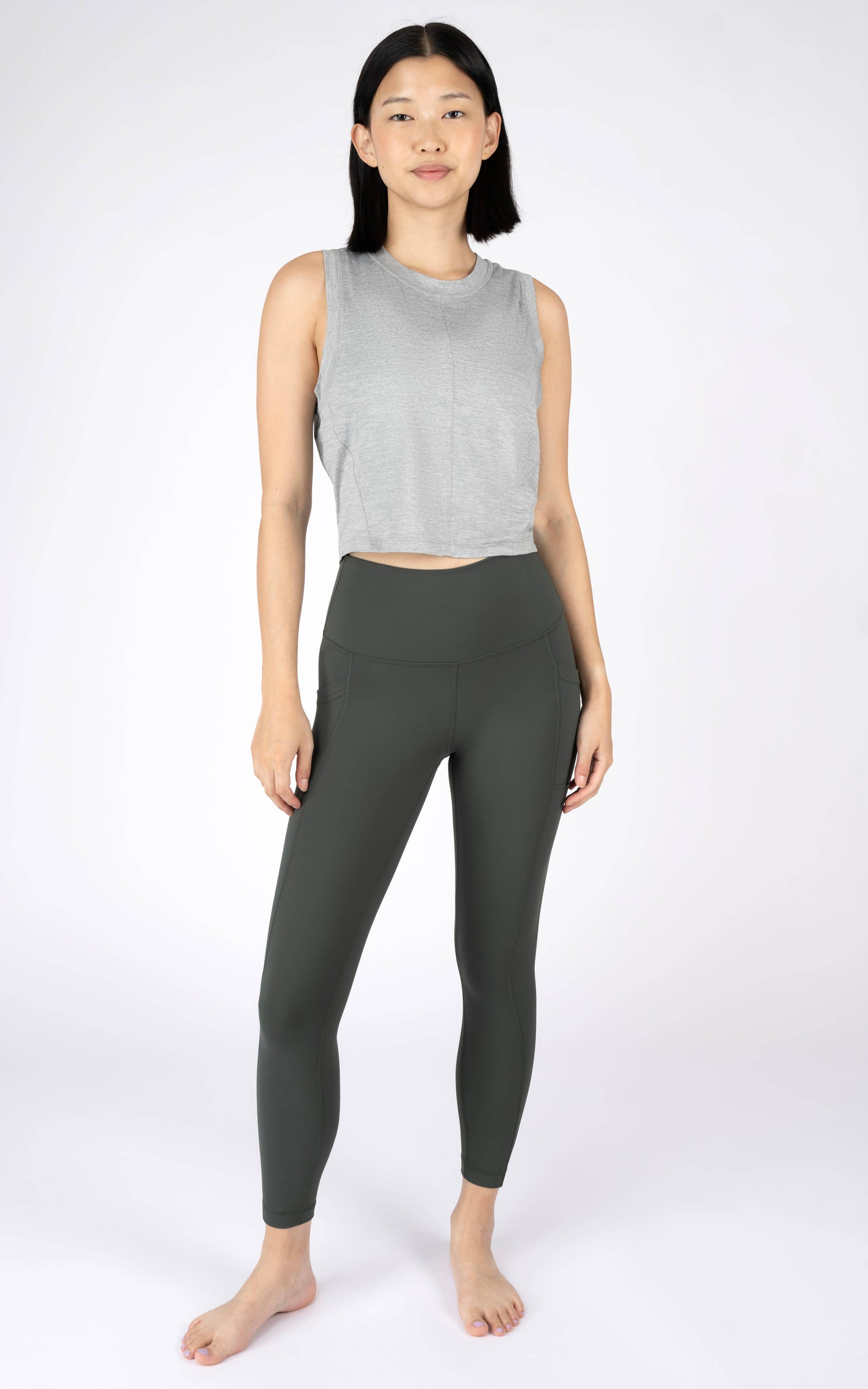 Woman wearing a gray sleeveless top and black leggings on a white background