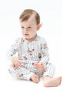 A baby sitting cross-legged wearing a white long-sleeve pajama set with thin dark pinstripes and small teddy bear illustrations, photographed on a clean white studio background.