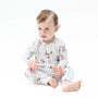 A baby sitting cross-legged wearing a white long-sleeve pajama set with thin dark pinstripes and small teddy bear illustrations, photographed on a clean white studio background.
