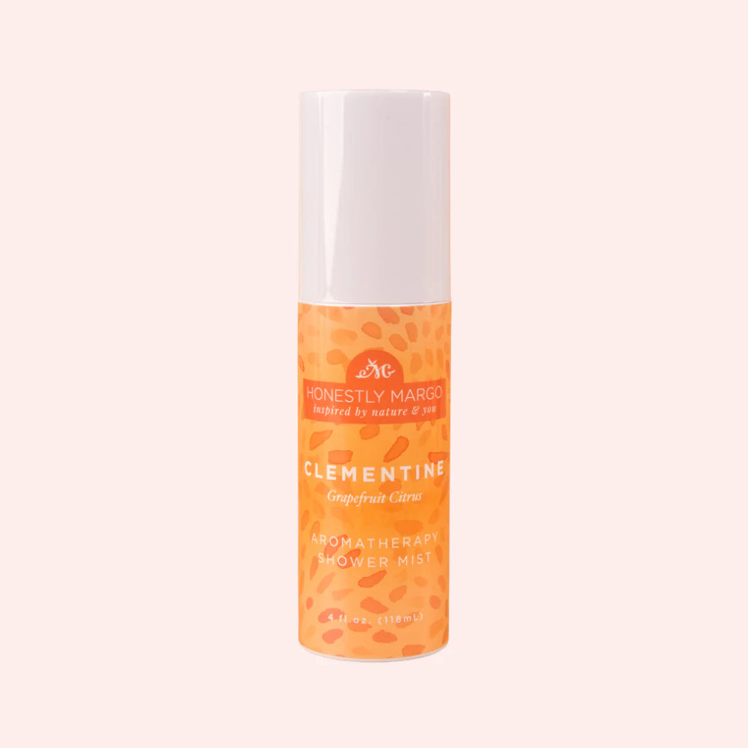 Orange and white bottle of Clementine Aromatherapy Flower Mist on a light pink background