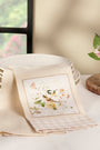 Decorative table setting with a folded napkin featuring a floral design, plates, and a vase with flowers.