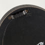 Close-up of a black circular object with a metal bracket and screws on a white background