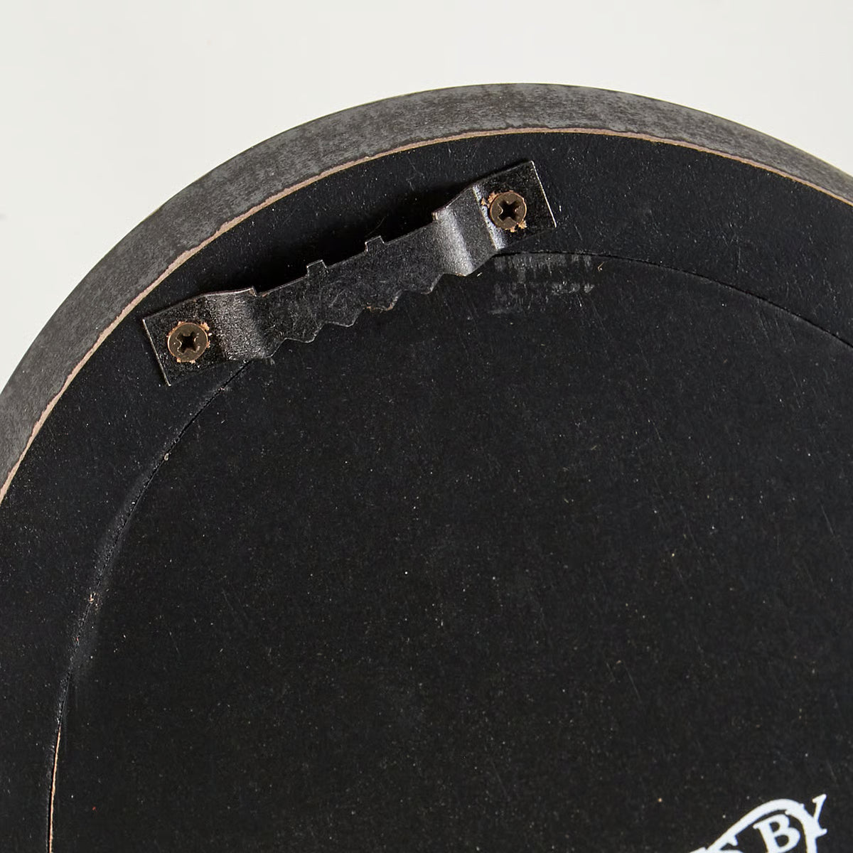 Close-up of a black circular object with a metal bracket and screws on a white background