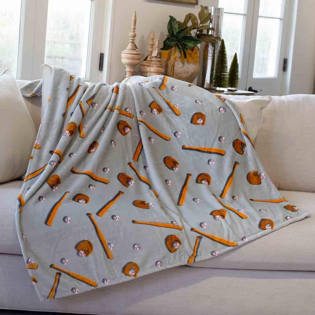 Blanket with baseball-themed pattern draped over a couch in a living room.