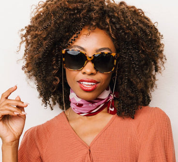 Woman wearing sunglasses and a pink top with a white background