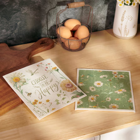 Two floral-themed greeting cards on a wooden surface with eggs and a basket in the background.