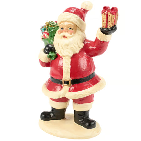 A painted Santa Claus figurine standing on a round base, wearing a red suit with white trim and holding a green wreath in one hand and a wrapped gift in the other, against a plain white background.