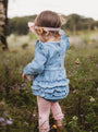 Child in a blue dress standing in a field with blurred background