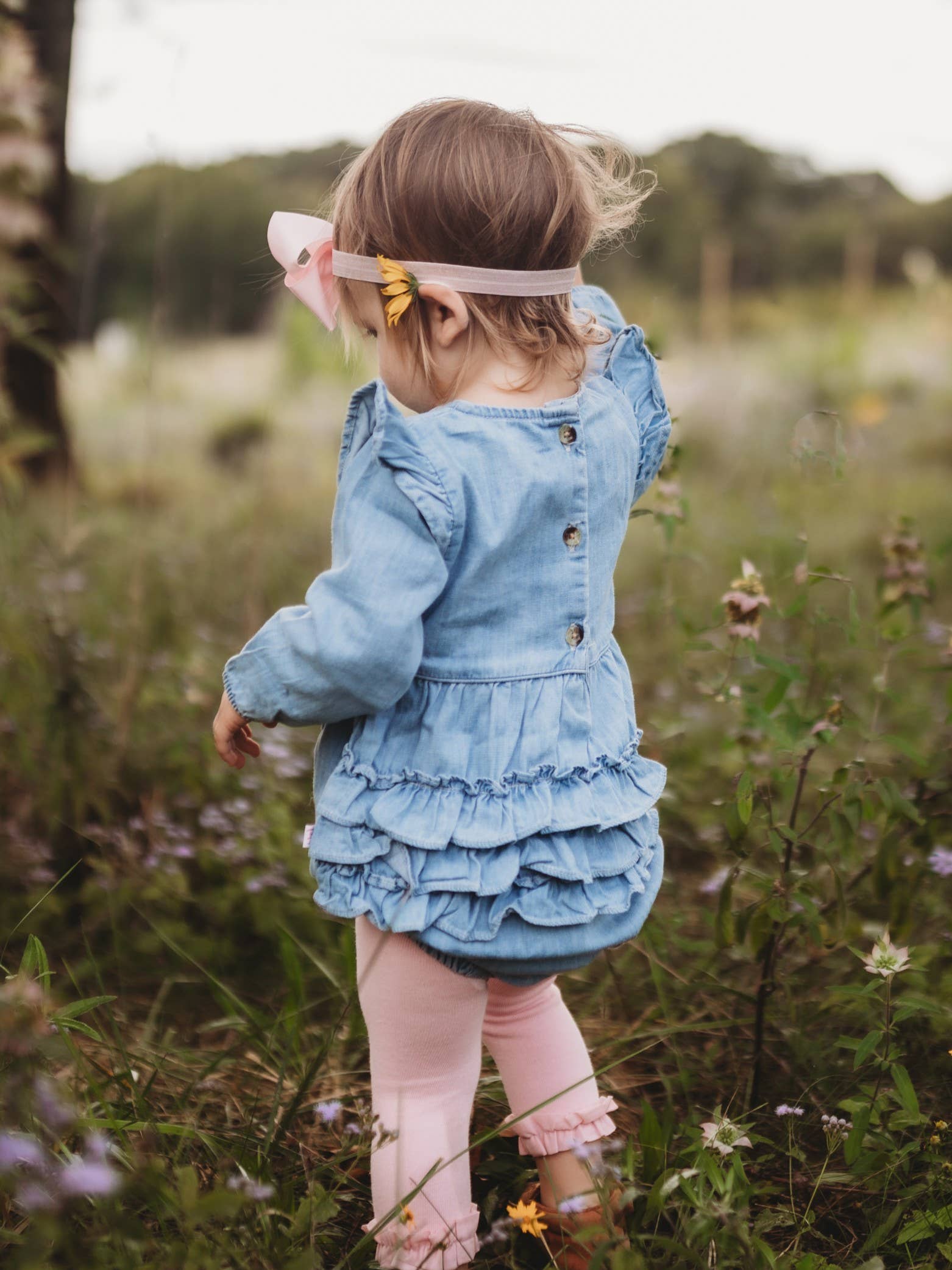 Child in a blue dress standing in a field with blurred background