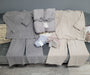Gray and beige bath towels on a gray sofa with price tags.