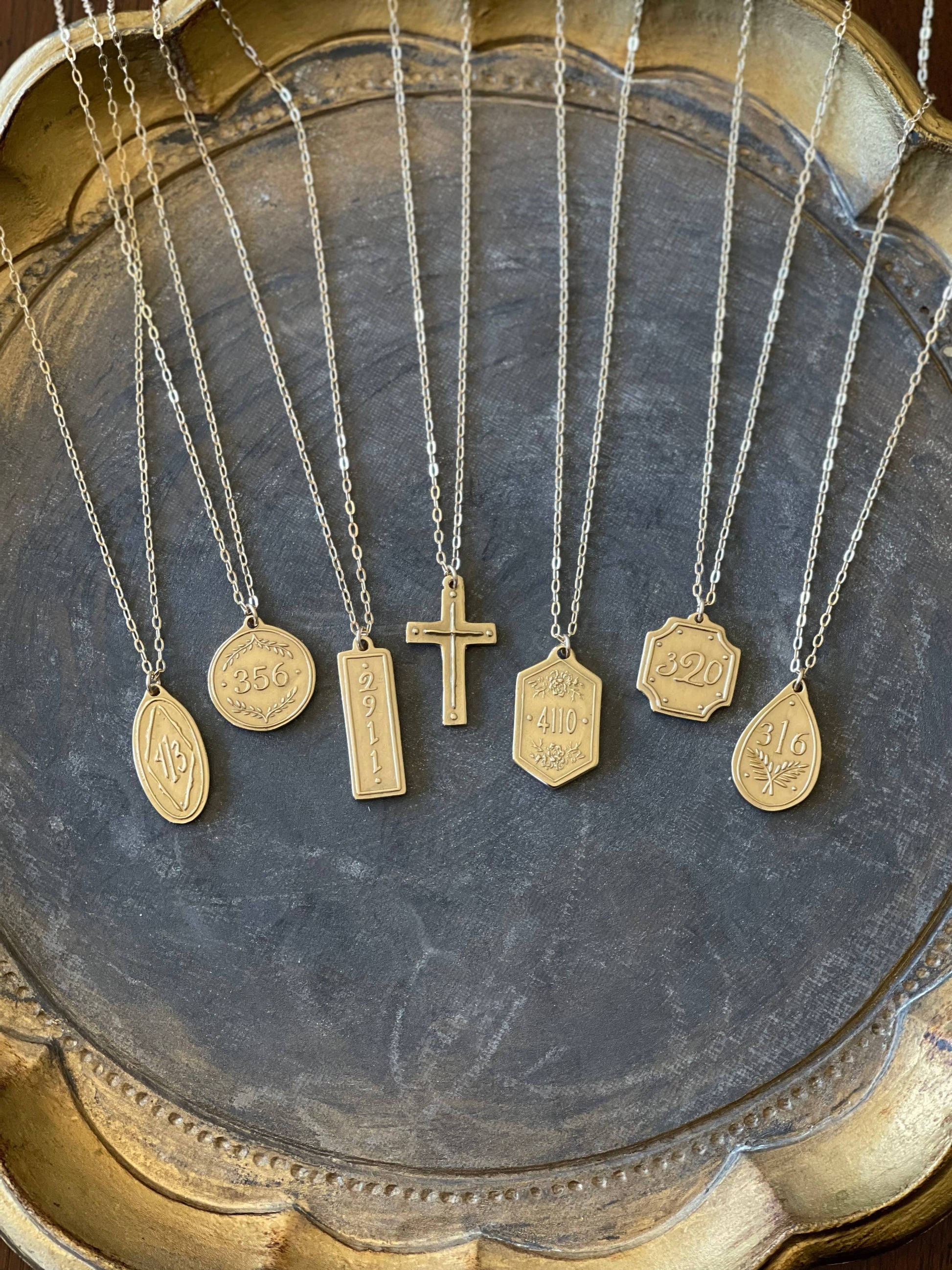 Gold necklaces with various pendants on a textured surface