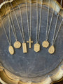 Gold necklaces with various pendants on a textured surface