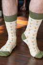 White socks with green tops and deer pattern worn by a person on a wooden floor.