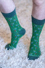 Green socks with golf-themed pattern worn on a carpeted floor