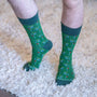 Green socks with golf-themed pattern worn on a carpeted floor