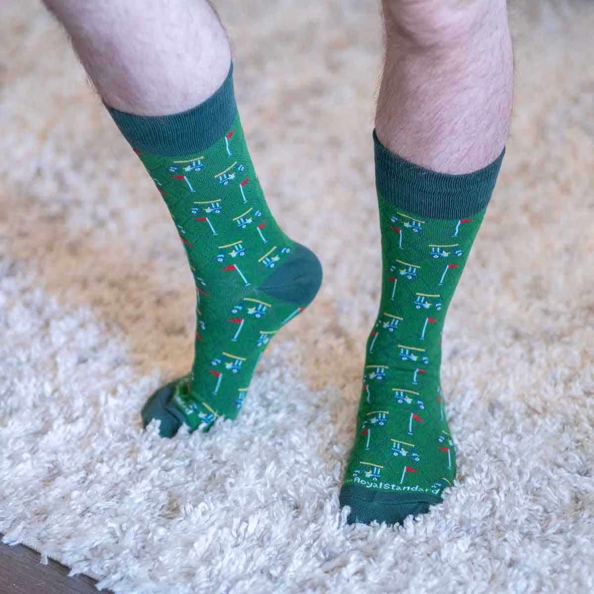 Green socks with golf-themed pattern worn on a carpeted floor