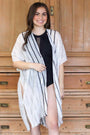 Woman wearing a white and black striped cover-up in front of wooden furniture.