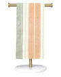 Striped towel hanging on a gold towel rack with a white base