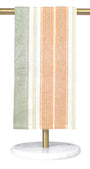 Striped towel hanging on a gold towel rack with a white base