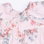 Floral patterned shirt with ruffled collar on a light pink background